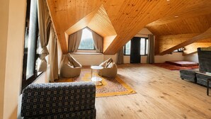 Una habitación con techos altos y un techo de madera inclinado, un ventanal grande y un sofá estampado.