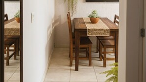A dining area with a wooden table, chairs, a potted plant, and a wall-mounted TV. - 450m from the beach. Functional apartment, 500MB Wi-Fi, garage, sleeps up to 5 people. (Balneário Camboriú)