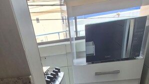 A kitchen with a microwave, stove, and cabinets. - 450m from the beach. Functional apartment, 500MB Wi-Fi, garage, sleeps up to 5 people. (Balneário Camboriú)