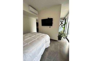 A bedroom with a bed, a mounted TV, an air conditioning unit, and a potted plant. - Cozy home office, loft in Guadalajara (Guadalajara)