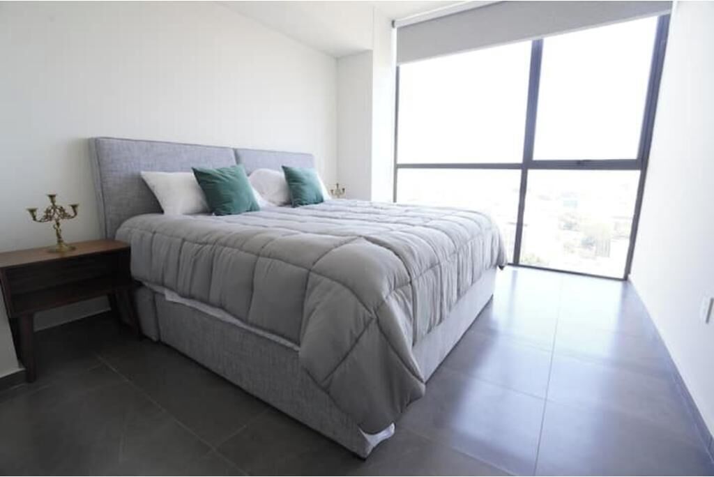 A bedroom with a bed, a nightstand, a window, and a chandelier.