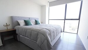 A bedroom with a bed, a nightstand, a window, and a chandelier. - Splendid apartment in the heart of Colonia Americana (Guadalajara)