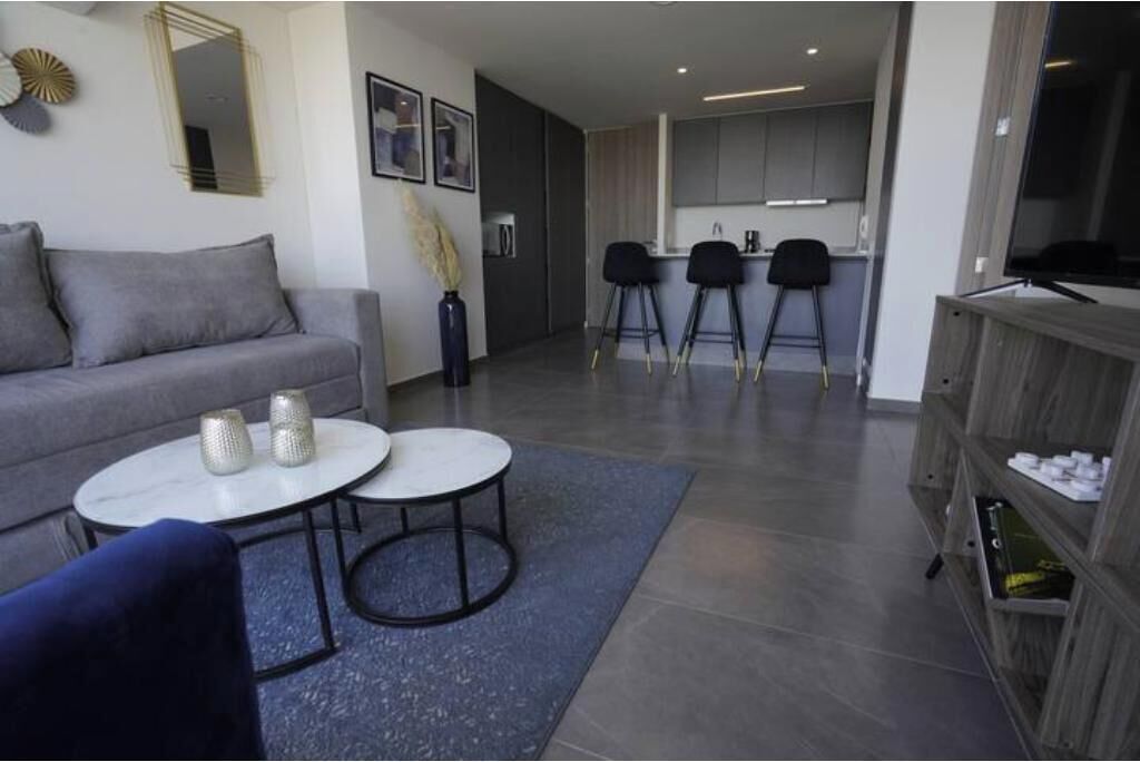 A modern living room with a sofa, two round tables, a coffee table, and a bookshelf.
