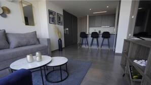 A modern living room with a sofa, two round tables, a coffee table, and a bookshelf. - Splendid apartment in the heart of Colonia Americana (Guadalajara)