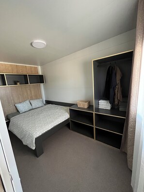 Une chambre à coucher avec un lit, une armoire, une table de chevet et un luminaire au plafond.