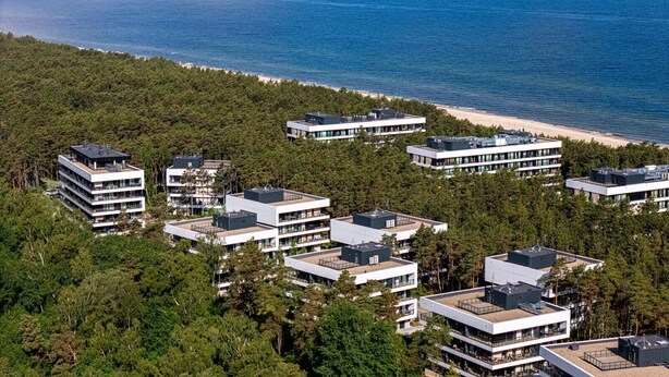 A modern residential complex with multiple buildings, surrounded by dense forest and a beach. - Oaza Spokoju | Widok na Las | Design | Shellter (Rogowo)