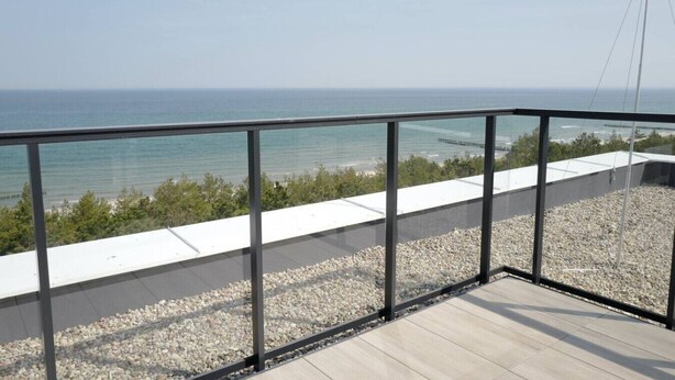 A balcony with a view of the sea, a wooden deck, and a glass railing. - Widok na Morze | Przy Plaży | Taras | Shellter (Rogowo)