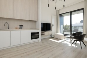 A modern kitchen with built-in appliances, a dining area with a table and chairs, and a large window offering a view of the outdoors. - Widok na Morze | Przy Plaży | Taras | Shellter (Rogowo)