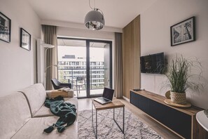 Una sala de estar moderna con sofá, mesa de centro, televisor y balcón con vista a la ciudad.