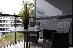 A balcony with a round table, two wicker chairs, a potted plant, and a decorative mug. - Puro Apartment | Shellter Rogowo | Taras, Las & Plaża (Rogowo)