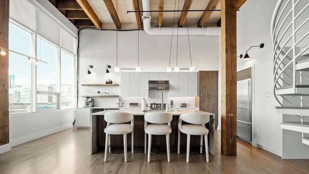Une cuisine moderne dotée d’un îlot central, de luminaires suspendus et offrant une vue sur la ville.