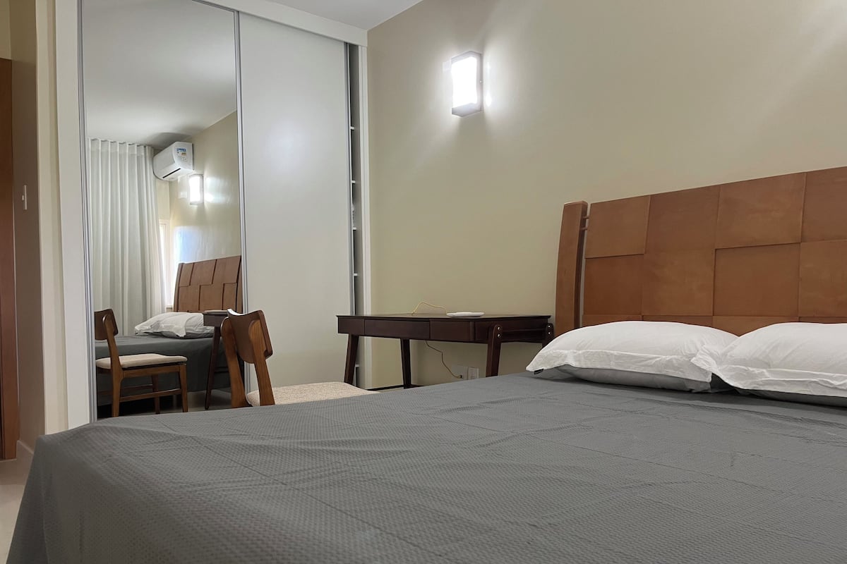 A bedroom with a bed, a desk, and a chair.