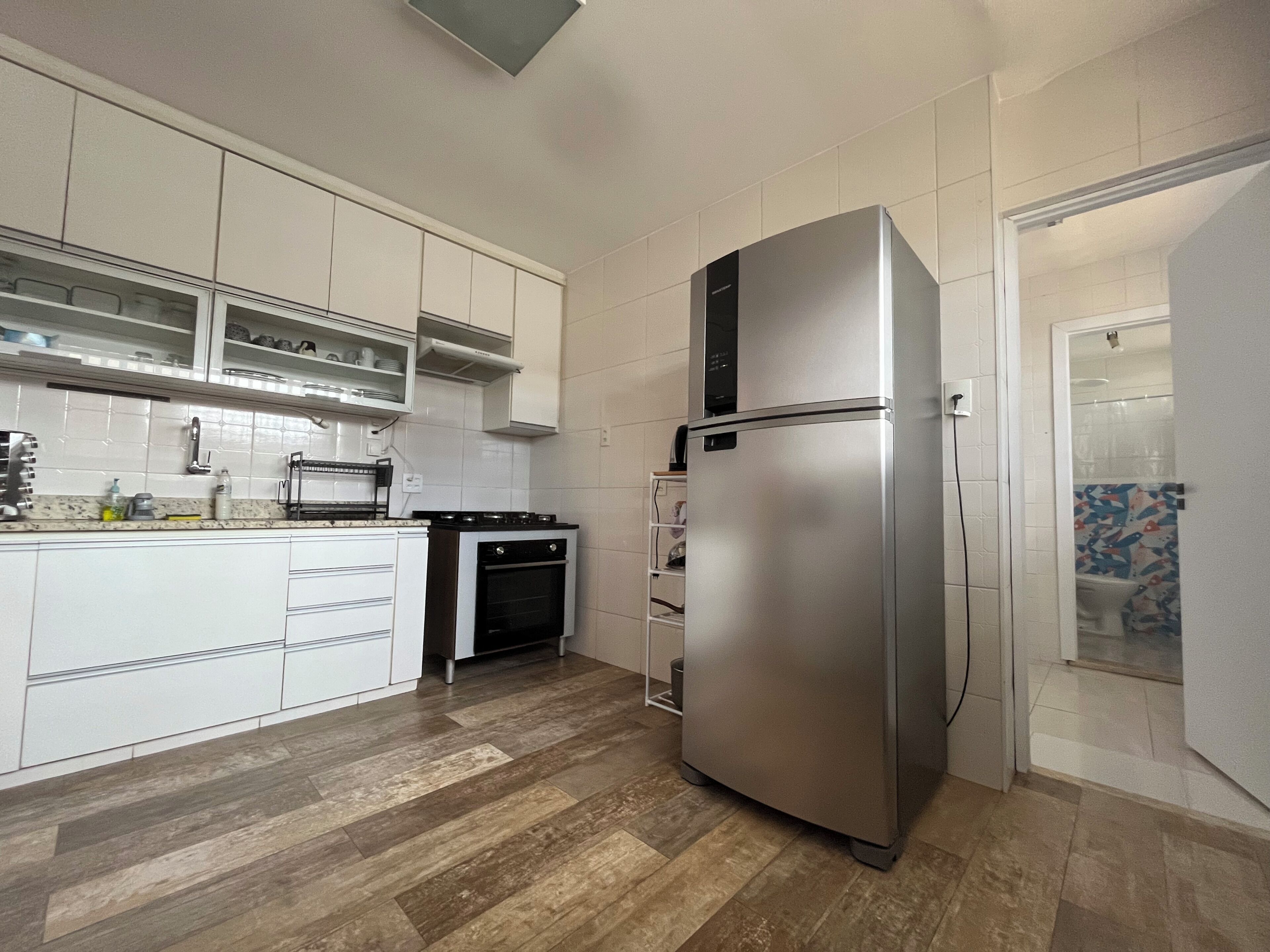 Una cucina moderna con mobili bianchi, un frigorifero in acciaio inossidabile, un forno integrato e un microonde.