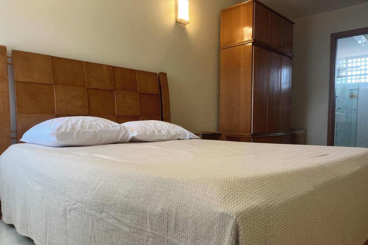 A bed with a headboard, pillows, and a wooden wardrobe.
