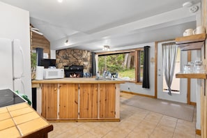 A kitchen with a stone fireplace, wooden counter, and a view of the outdoors.