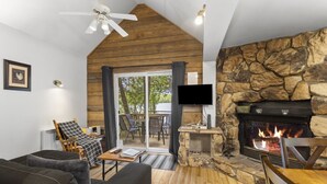 Una sala de estar acogedora con chimenea, televisor y techo de madera.