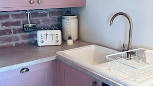 A kitchen with a sink, a toaster, a bread container, and a brick wall. - Farnah House Barn (Belper)