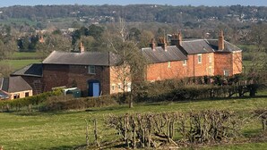 A rural house with a brick exterior, a blue door, and a chimney. - Farnah House Barn (Belper)