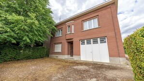 A two-story brick house with a garage, surrounded by greenery. - Villa Jules (Holsbeek)