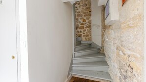 A staircase with a stone wall and a white door. - Spacious studio, chic and quiet, attractive Bon Marché district (Paris)