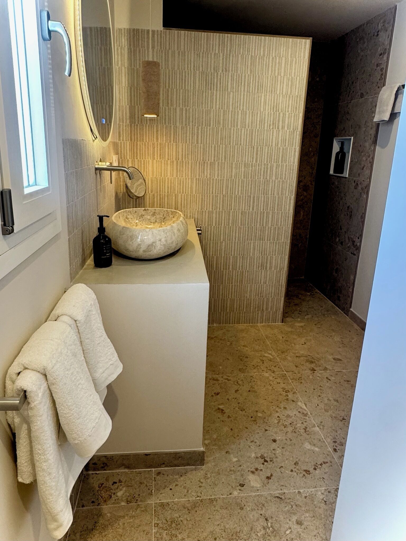 A bathroom with a round sink, a towel rack, and a mirror.