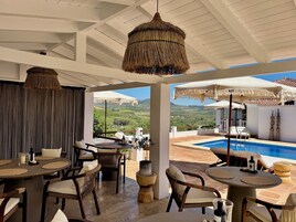 Amplio espacio al aire libre con piscina, mesas y sillas para comer, con vistas a un paisaje pintoresco.