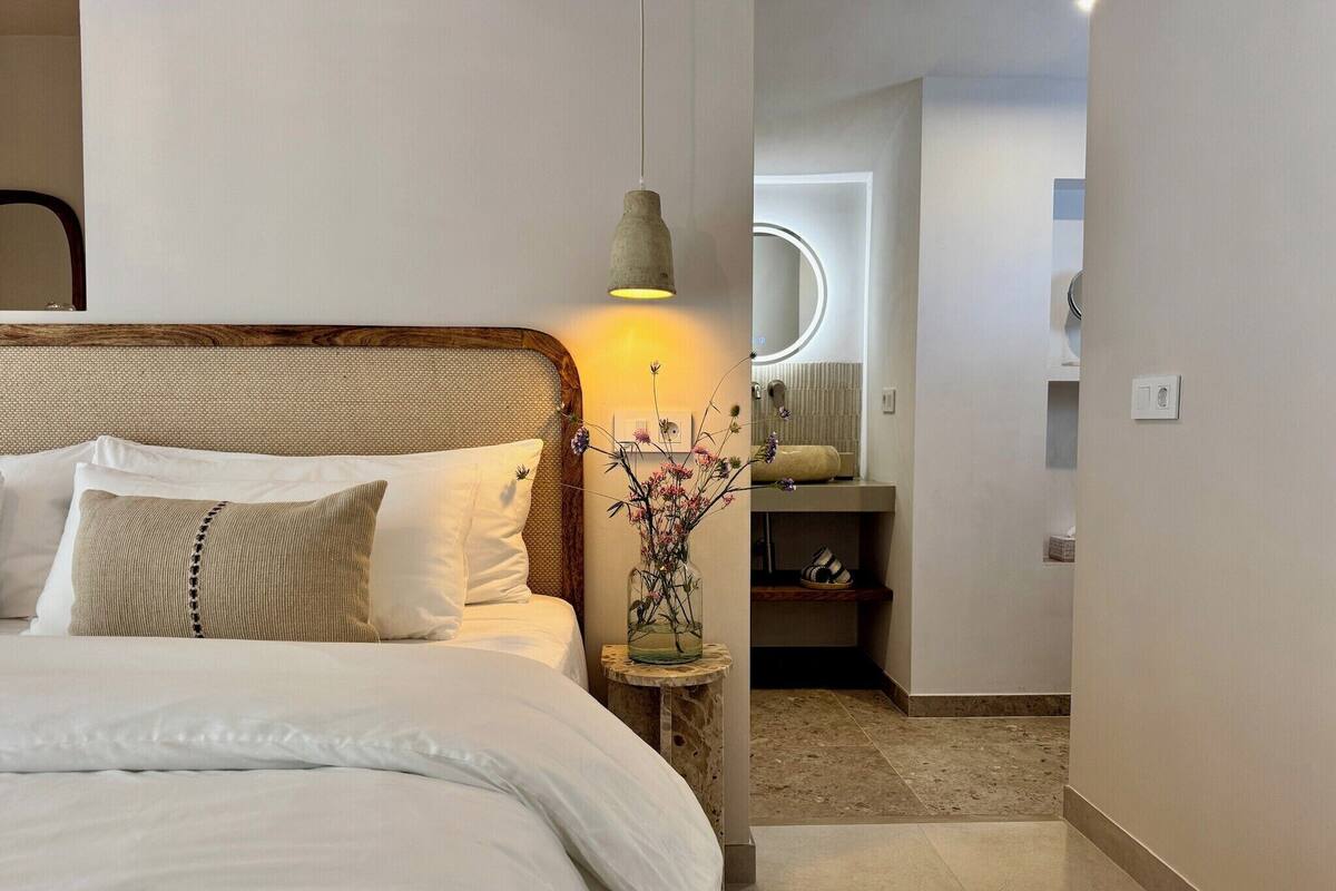 Ein Schlafzimmer mit einem Bett, Nachttisch, Lampe und Spiegel.