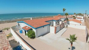A coastal property with a red-tiled roof, a white garage, and a view of the ocean. - Beautiful Beachfront Home Casa de Veranos (Puerto Peñasco)