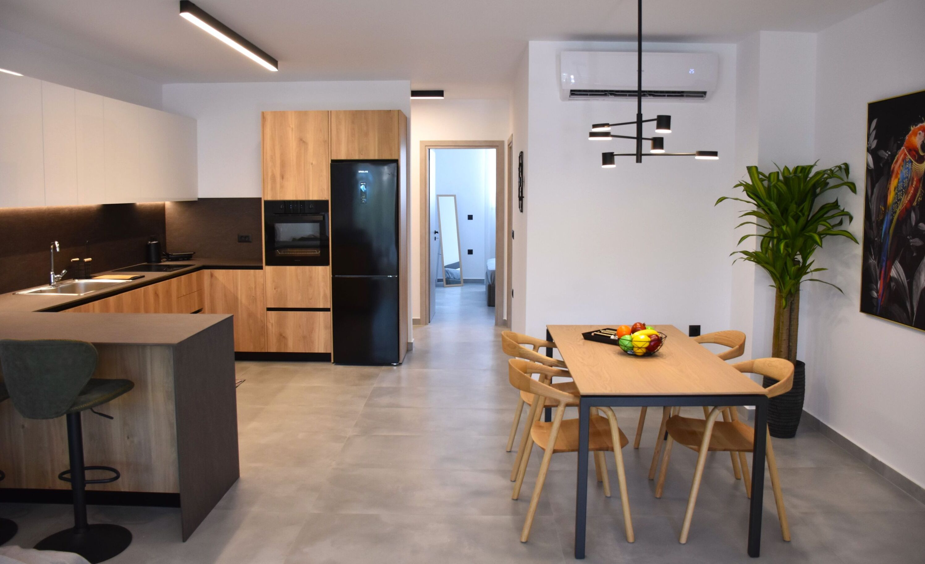 A modern kitchen with wooden cabinets, a black refrigerator, and a dining area with a table and chairs.