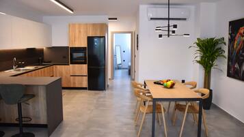 A modern kitchen with wooden cabinets, a black refrigerator, and a dining area with a table and chairs.