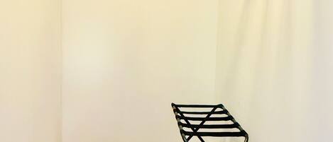 A small, well-organized closet with a hanging rack, a bench, and a shelf.