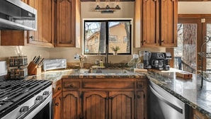Una cocina con armarios de madera, estufa integrada, un lavabo y una ventana.