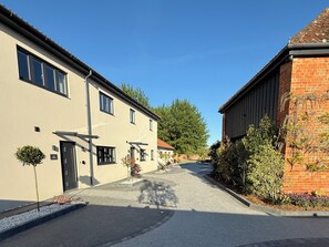 Eine Straße mit Gebäuden, darunter ein zweistöckiges Haus mit Garage und einem kleineren Anbau.