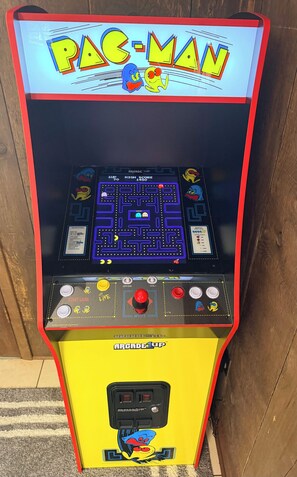 A Pac-Man arcade machine with a maze game, score display, and control buttons.