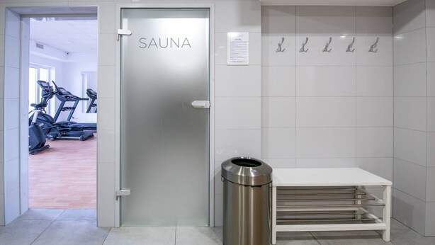 Una camera moderna e pulita con porta della sauna, attrezzature per esercizi e un cestino.