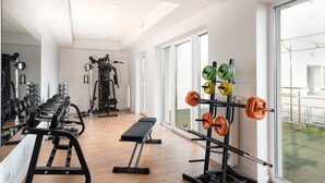Una palestra con attrezzature per sollevamento pesi, una panca e ampie finestre.