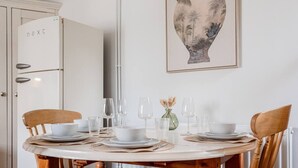 Een eettafel gedekt met borden, glazen en een vaas met gedroogde bloemen.