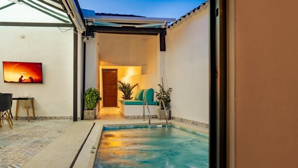 A pool area with a chair, a small table, and a television mounted on the wall.
