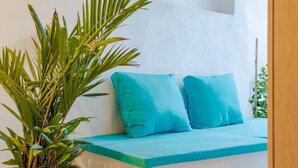 A room with a bed, two blue pillows, a potted plant, and a white wall.