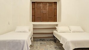 A room with two beds, a wooden wardrobe, and patterned floor tiles.