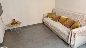 A living room with a sofa, a small side table, and a decorative vase. - Apartment T2/3 Corte center (Corte)