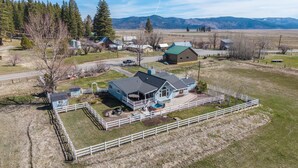 A large house with a fenced yard, a swimming pool, and a view of mountains. - Mountain View Escape | Hot Tub, Fire Pit & Games (Sattley)