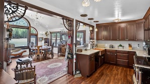 A spacious kitchen with wooden cabinets, a large island, and a dining area with a chandelier. - Mountain View Escape | Hot Tub, Fire Pit & Games (Sattley)