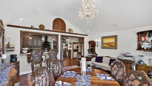 A dining room with a wooden table, floral upholstered chairs, a chandelier, and a large mirror. - Mountain View Escape | Hot Tub, Fire Pit & Games (Sattley)