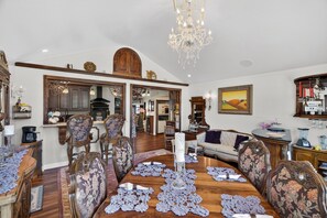 A dining room with a wooden table, floral upholstered chairs, a chandelier, and a large mirror.