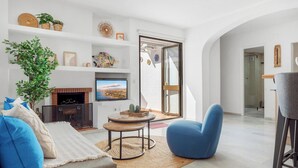 Ein modernes Wohnzimmer mit Kamin, Fernseher, einem blauen Sessel und einem großen Fenster.