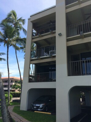 A multi-story building with balconies, a car parked in a covered parking area, and palm trees in the background. - Amazing condo in beautiful Kailua-Kona!
Ocean-Front, right on the water's edge. (Kailua-Kona)