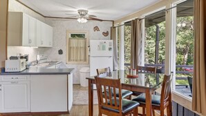 Une cuisine compacte avec un coin repas, un ventilateur de plafond et une vue sur l’extérieur.