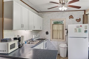 A compact kitchen with white cabinets, a microwave, a stove, and a ceiling fan. - Luray retreat - Hiking and Shenandoah River nearby - Dog friendly (Page County)