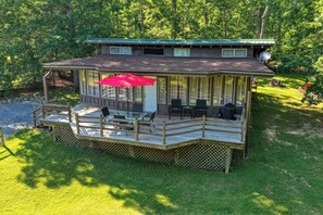 A wooden deck with outdoor furniture and a red umbrella, surrounded by a forested area. - Luray retreat - Hiking and Shenandoah River nearby - Dog friendly (Page County)